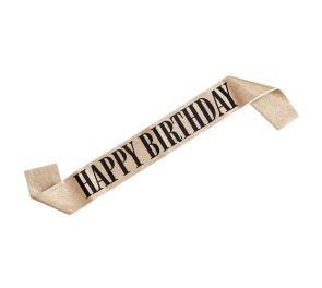 Kultaisella glitterillä päällystetty olkanauha, missä mustalla tekstillä Happy birthday